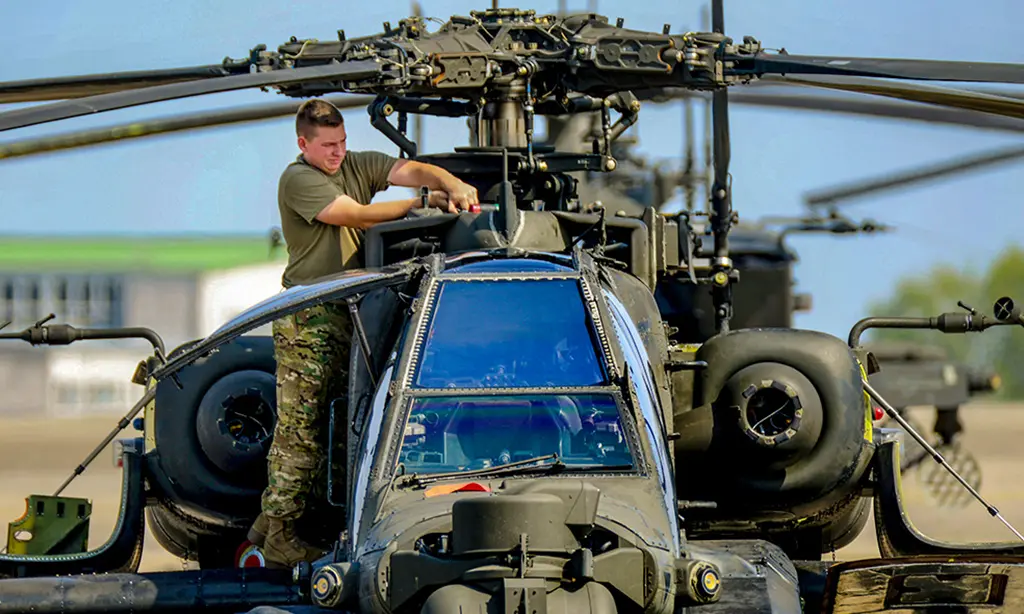 military man working on apache helicopter